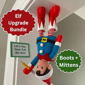 May include: An upside-down elf doll wearing a blue sweater, red boots, and mittens. The elf has a red and white striped hat and is holding a pencil. Text on the image reads "Elf Upgrade Bundle", "Let's See How Tall We Are!", and "Boots + Mittens".