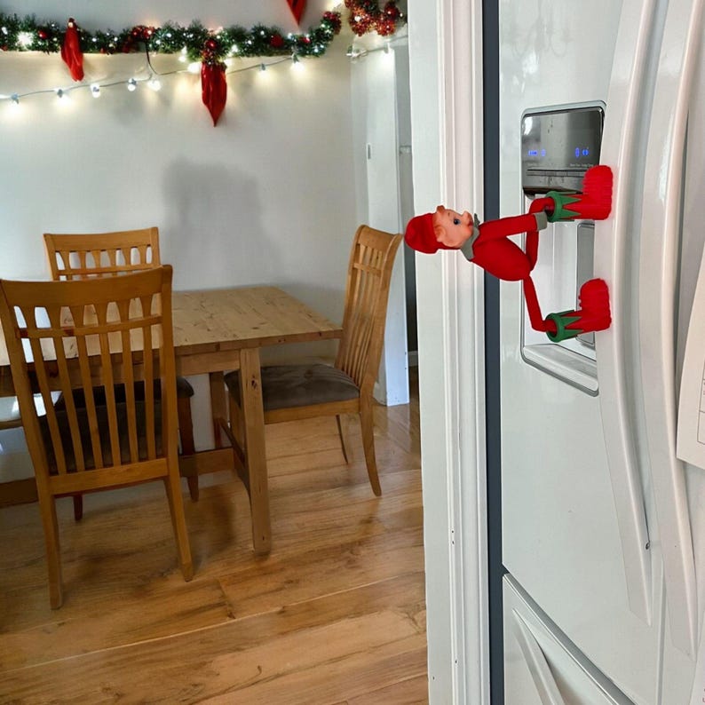 A Christmas Elf climbing up a refrigerator wearing his Enchanted Elf Boots.