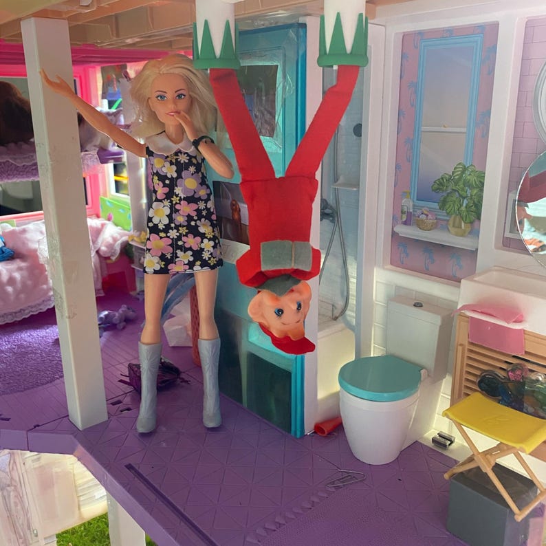 A Christmas Elf walking on the ceiling of a doll house wearing his Enchanted Elf boots.