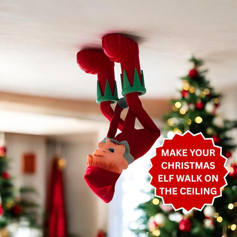 May include: A red and green elf figurine attached to a ceiling, wearing a red hat and green collar. A red starburst graphic with white text reads: MAKE YOUR CHRISTMAS ELF WALK ON THE CEILING. The elf is positioned upside down with feet upward.