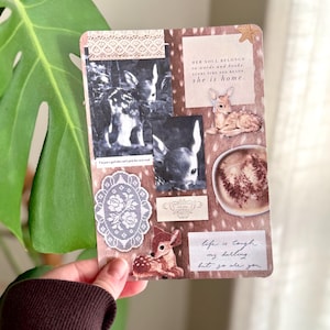 May include: A decorative journal page with a deer theme. It features black and white photos of deer, a lace trim, and various quotes, including "HER SOUL BELONGS to words and books. EVERY TIME SHE READS she is home." and "life is tough my darling, but so are you."