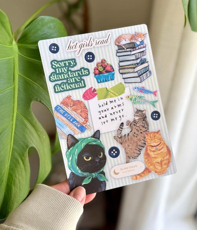 May include: A decorative sticker sheet featuring cat illustrations and text. The sheet includes images of cats, books, and phrases like "hot girls read" and "Sorry, my standards are fictional." The design incorporates blue, green, and orange accents.