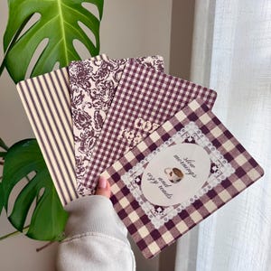 May include: A set of four rectangular cards with rounded corners, featuring various patterns in dark brown and cream. Designs include vertical stripes, a floral print, and a gingham check. One card displays a central oval with lace trim and the text "slow mornings and cozy reads" alongside a small illustration of a coffee mug.