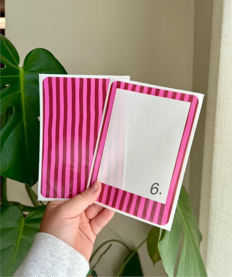 May include: Two white cards with pink and burgundy striped borders and accents. One card has a blank white space, the other has a vertical striped pattern. The number "6." is printed on the blank card.
