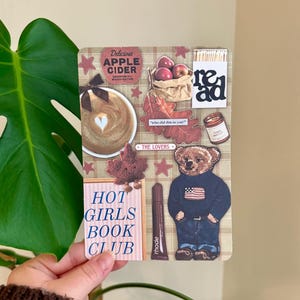 May include: A collage featuring various stickers and images. Includes a coffee cup with a heart design, a bag of apples, a bear wearing a sweater, and the text "HOT GIRLS BOOK CLUB". Other text includes "Delicious Apple Cider" and "read".