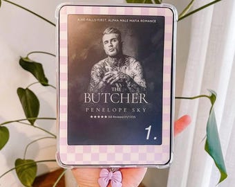 May include: A digital e-reader device featuring a light purple and white checkered protective case. The screen displays a book cover titled The Butcher by Penelope Sky, featuring a tattooed person, with a small light purple bow charm attached.
