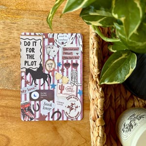 以下が含まれることがあります： カウボーイをテーマにした装飾カード。カードには、馬に乗る人のシルエット、さまざまなステッカー、テキスト（「Do it for the plot」、「cool it cowboy」、「Cowboy Country」など）が描かれています。背景はストライプ模様です。