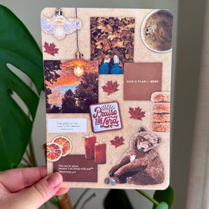 May include: A collage featuring a bear illustration, maple leaves, and the text "Praise the Lord." Other elements include a cup of coffee, candles, and the text "GOD'S PLAN > MINE." The collage has a warm, earthy color palette.
