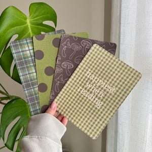 Op de afbeelding: Een set van vier rechthoekige bladwijzers met afgeronde hoeken. De ontwerpen bevatten een groen en bruin ruitpatroon, een groene achtergrond met bruine stippen, een donkerbruine achtergrond met witte paddenstoelillustraties en een groen vichy-ruitje.