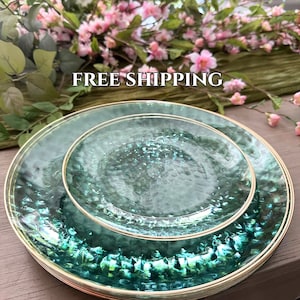 May include: Set of four green glass dinner plates with a gold rim. The plates have a textured surface and a subtle iridescent sheen.