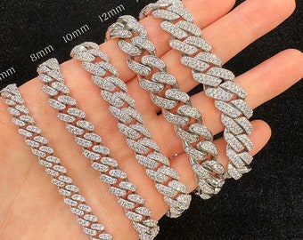 May include: Five silver Cuban link chains with varying widths, from 6mm to 14mm, are displayed on a hand. Each chain is adorned with small, clear cubic zirconia stones.