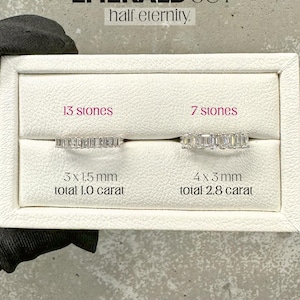 K&ouml;nnte beinhalten: Zwei Diamant-Ringe im Smaragdschliff in einer wei&szlig;en Box. Der Ring links hat 13 Steine, ist 3 x 1,5 mm gro&szlig; und wiegt 1,0 Karat. Der Ring rechts hat 7 Steine, ist 4 x 3 mm gro&szlig; und wiegt 2,8 Karat. Der Text "EMERALD CUT half eternity" befindet sich oben im Bild. Der Text "AMELIA MINIMALIST moissanite jewellery" befindet sich unten im Bild.