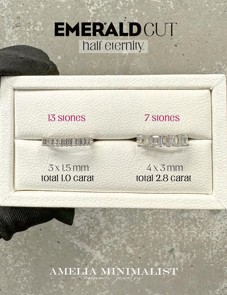 K&ouml;nnte beinhalten: Zwei Diamant-Ringe im Smaragdschliff in einer wei&szlig;en Box. Der Ring links hat 13 Steine, ist 3 x 1,5 mm gro&szlig; und wiegt 1,0 Karat. Der Ring rechts hat 7 Steine, ist 4 x 3 mm gro&szlig; und wiegt 2,8 Karat. Der Text "EMERALD CUT half eternity" befindet sich oben im Bild. Der Text "AMELIA MINIMALIST moissanite jewellery" befindet sich unten im Bild.