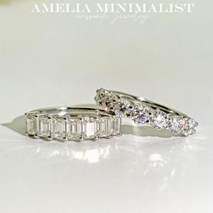 K&ouml;nnte beinhalten: Zwei silberne Ringe mit klaren Edelsteinen. Der obere Ring hat runde Edelsteine und der untere Ring hat rechteckige Edelsteine. Amelia Minimalist Moissanite Jewelry.