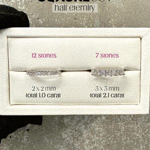 K&ouml;nnte beinhalten: Zwei wei&szlig;e Ringboxen mit Diamantringen. Die obere Box enth&auml;lt einen Ring mit 12 Steinen, 2 x 2 mm, insgesamt 1,0 Karat. Die untere Box enth&auml;lt einen Ring mit 7 Steinen, 3 x 3 mm, insgesamt 2,1 Karat. Die Boxen sind mit "SQAURECUT half eternity", "12 stones", "7 stones", "2 x 2 mm total 1.0 carat" und "3 x 3 mm total 2.1 carat" beschriftet.