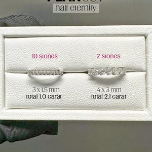 K&ouml;nnte beinhalten: Zwei birnenf&ouml;rmige Diamantringe auf einem wei&szlig;en Display. Der Ring links hat 10 Steine, ist 3 x 1,5 mm gro&szlig; und 1,0 Karat schwer. Der Ring rechts hat 7 Steine, ist 4 x 3 mm gro&szlig; und 2,1 Karat schwer. Der Text "PEAR CUT half eternity" befindet sich oben auf dem Display. Der Text "AMELIA MINIMALIST noissanife jewellery" befindet sich unten auf dem Display.