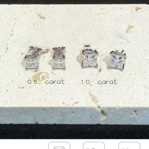 Puede incluir: Cuatro pendientes de bot&oacute;n plateados con piedras transparentes de corte cuadrado. Dos est&aacute;n etiquetados como 0,5 quilates y dos como 1,0 quilates. El texto incluye 'amelia minimalist', 'CLASSIC Square', 'Square Cut', '0.5 Ct each weight 4.3x4.3mm' y '1.0 Ct each weight 5.5x5.5mm'.