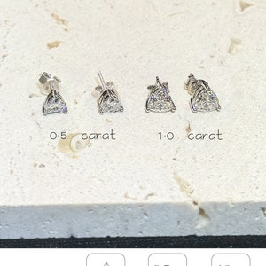 Puede incluir: Cuatro pendientes de bot&oacute;n plateados con piedras transparentes de corte triangular. Dos pendientes est&aacute;n marcados como 0.5 quilates y dos como 1.0 quilates. El texto incluye amelia minimalist, CLASSIC Triangle, Triangle Cut, 0.5 Ct each weight 5x5mm, 1.0 Ct each weight 6.5x6.5mm.