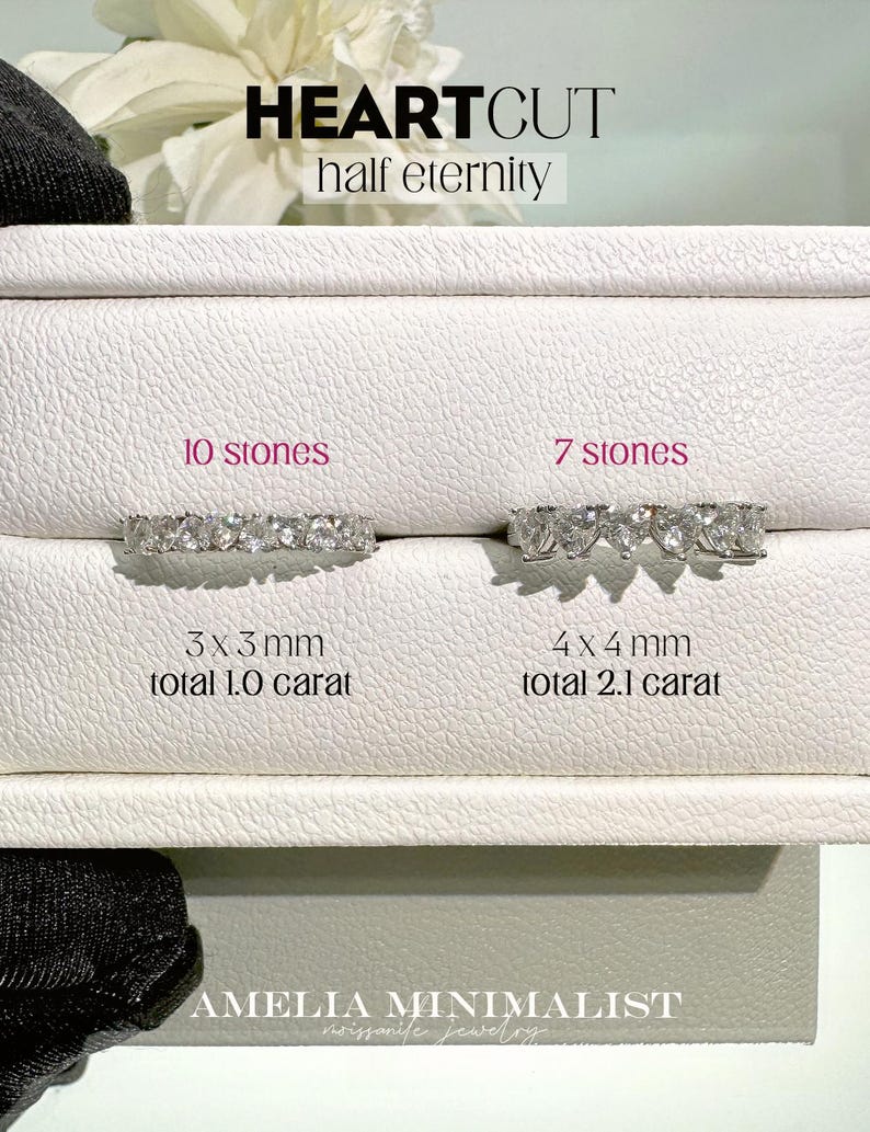 K&ouml;nnte beinhalten: Zwei silberne Ringe mit herzf&ouml;rmigen Diamanten. Der Ring links hat 10 Steine, jeder 3 mm gro&szlig;, f&uuml;r insgesamt 1,0 Karat. Der Ring rechts hat 7 Steine, jeder 4 mm gro&szlig;, f&uuml;r insgesamt 2,1 Karat. Die Ringe sind mit "HEARTCUT half eternity" beschriftet.