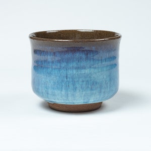 May include: A blue and brown ceramic teacup with a crackled glaze.