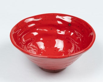 May include: A red ceramic bowl with a wavy, textured surface. The bowl is empty and has a glossy finish.