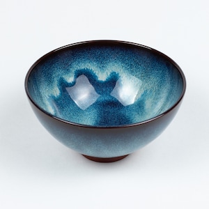 May include: A blue and brown ceramic bowl with a speckled glaze. The bowl is round and has a wide rim.