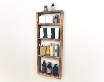 May include: A rustic wooden shelf unit with four shelves. The shelves are filled with various items, including towels, toiletries, and plants. The shelf unit is mounted on a white wall.