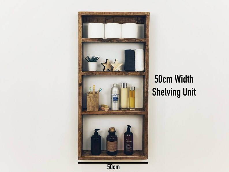 May include: A rustic wooden shelf unit with four shelves, measuring 50cm wide. The shelves are filled with various items, including toilet paper, plants, toiletries, and decorative stars. The unit is labeled "50cm Width Shelving Unit".