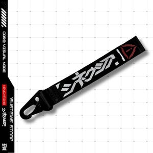 May include: Black keychain strap with white Japanese text and a red triangle design. The strap has a metal clasp and the text "SYSTEMS" STRAP is printed on the side.