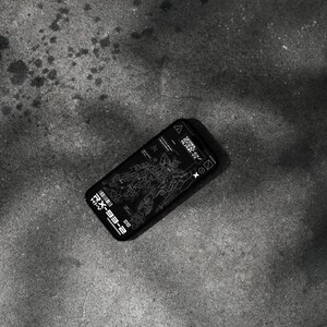 May include: Black smartphone case featuring a detailed white schematic of a robot, with the text "RX-93-2" and other technical markings. The case is lying on a textured gray surface.