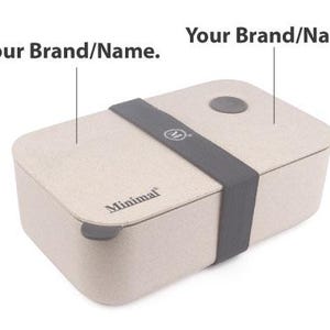 May include: A rectangular beige lunch box with a speckled texture, featuring a dark gray elastic band across the center, a small circular gray vent on the lid, and the word Minimal printed in black on the front edge with Your Brand/Name text labels.