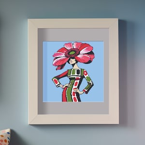 以下が含まれることがあります： 額縁に入ったイラスト。女性が大きなピンクの花を帽子としてかぶっている。女性は緑と赤のドレスを着ており、白いアクセントが付けられている。背景は薄い青色です。