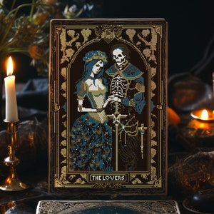 A digital render of 'The Lovers' Tarot cross stitch design. Presented in the format of tarot card on a table with candles. Strong black, white and blue DMC thread colours.
