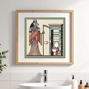 May include: Cross-stitch art in a wooden frame. The artwork depicts a skeletal figure with a scythe, standing before a toilet and a shelf with hieroglyphs. The color palette includes beige, red, black, and green.