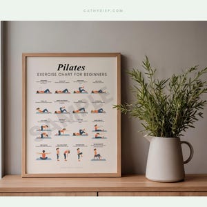 May include: A framed Pilates exercise chart for beginners. The chart displays illustrations of different exercises. A white vase with green plants is on a wooden surface beside the framed chart. The wall is a neutral grey colour.
