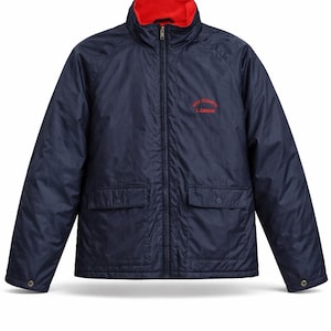 May include: Navy blue jacket with a red collar and lining. The jacket has a full zipper, two front pockets, and a small red logo on the chest. A classic outerwear piece.