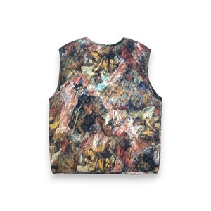 May include: A quilted vest featuring a Renaissance-style painting print in shades of brown, red, and gold. The sleeveless garment has a diamond pattern and a black trim, offering a unique artistic flair.