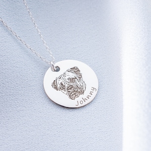 May include: A silver pendant necklace with a circular charm engraved with a dog's portrait. The dog's name, "Johnny", is inscribed below the image. The necklace has a fine silver chain.
