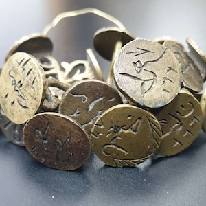 May include: A collection of antique brass seals with intricate designs and Arabic script. The seals are linked together by a metal ring.
