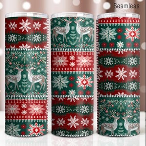 Può includere: Un set di tre bicchieri in acciaio inossidabile con un design natalizio. I bicchieri presentano un motivo ripetuto di cervi, fiocchi di neve e forme geometriche in rosso, verde e bianco. La parola "Seamless" è stampata in alto.