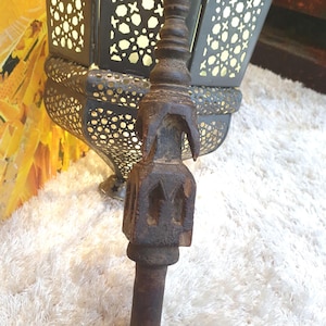 Peut inclure: Un objet en bois sculpté, brun foncé, avec une base cylindrique et un dessus décoratif. Le dessus présente une série d'éléments arrondis empilés et un motif sculpté. L'objet est posé sur un fond doux et blanc texturé.