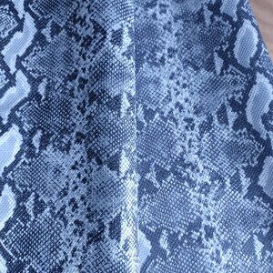 Könnte beinhalten: Nahaufnahme eines blauen und weißen Stoffes mit Schlangenhautmuster.