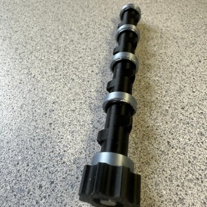 May include: A black and silver metal rod with a star-shaped knob at the end. The rod has five silver rings spaced evenly along its length.