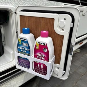 Op de afbeelding: Een witte kunststof opberghouder gemonteerd aan de binnenzijde van een camperdeur, met twee flessen Thetford chemische vloeistof. Eén fles is gelabeld Aqua Kem Blue Concentrated met een blauwe dop, de andere Aqua Rinse met een roze dop.