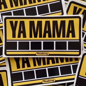 Peut inclure: Une pile d'autocollants jaunes et noirs avec le texte "Ya Mama" et le logo "Death Trap".