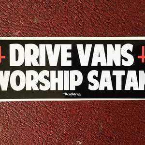 May include: Black and white sticker with the text "DRIVE VANS + WORSHIP SATAN" in white letters with a red cross on either side of the text. The text "Death Trap" is in smaller white letters below the main text.