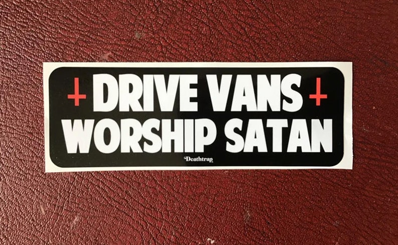 May include: Black and white sticker with the text "DRIVE VANS + WORSHIP SATAN" in white letters with a red cross on either side of the text. The text "Death Trap" is in smaller white letters below the main text.
