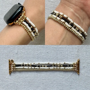 May include: Gold-toned beaded Apple Watch band with white, black, and gold beads. The band is shown on a wrist and also laid flat. The band has a multi-strand design with a secure clasp for easy attachment to the watch.