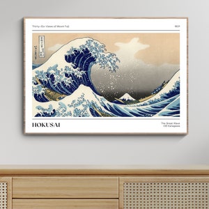 May include: A woodblock print of a large wave crashing over three boats with Mount Fuji in the background. The print is titled "The Great Wave off Kanagawa" and is attributed to Hokusai. The print is framed in a light wood frame.