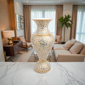 Puede incluir: Un jarrón decorativo alto con una boca ancha y una base bulbosa. El jarrón está adornado con un patrón detallado de pequeños diseños florales coloridos sobre un fondo crema. Bandas doradas rodean la parte superior e inferior, agregando elegancia.